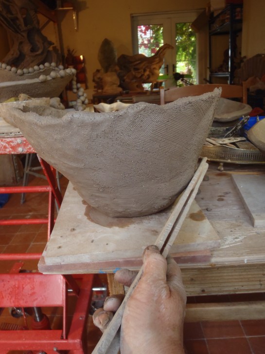 Sit back and look at the outline of your form. Use a paddle (flat stick) to tap in bumps or bulges. Rotate around the whole form in stages so that the stress of this action is spread evenly through the clay. Paddling compacts the clay particles making your form very strong. But over-doing it on one area can lead to cracks because it alters the drying rate.